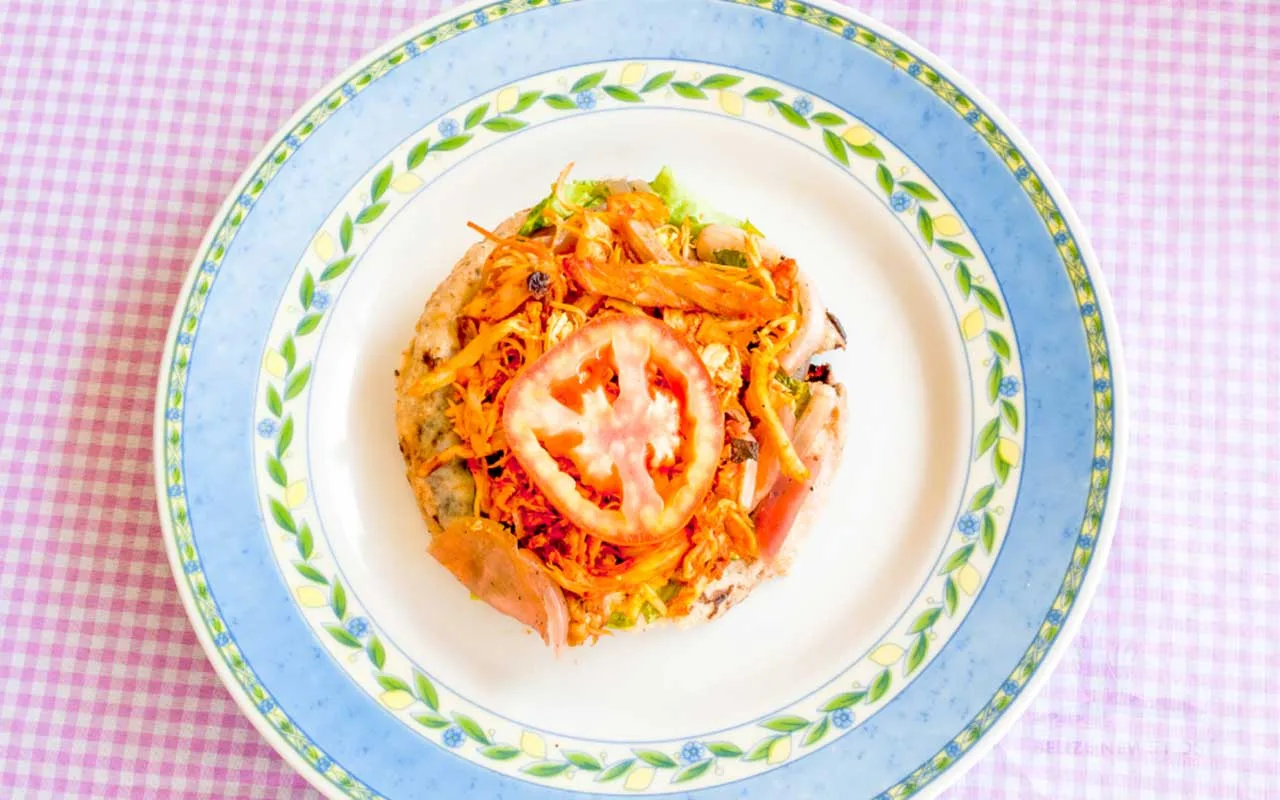 Salbutes, soft puffed fried tortillas topped with chicken, cabbage, and pickled onion