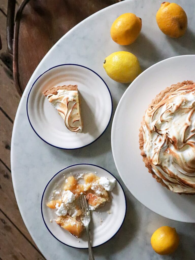 tart with meringue on plates near lemons on table