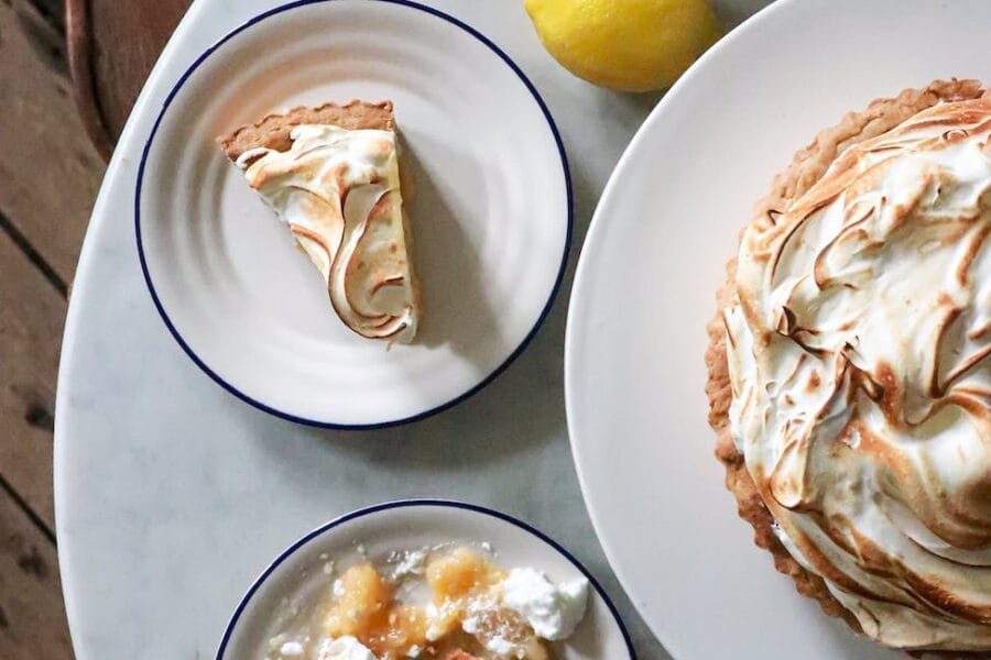 tart with meringue on plates near lemons on table