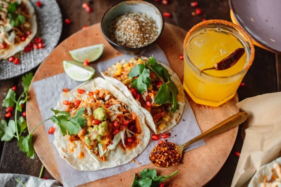 tacos on a cutting board juice in glass and spices