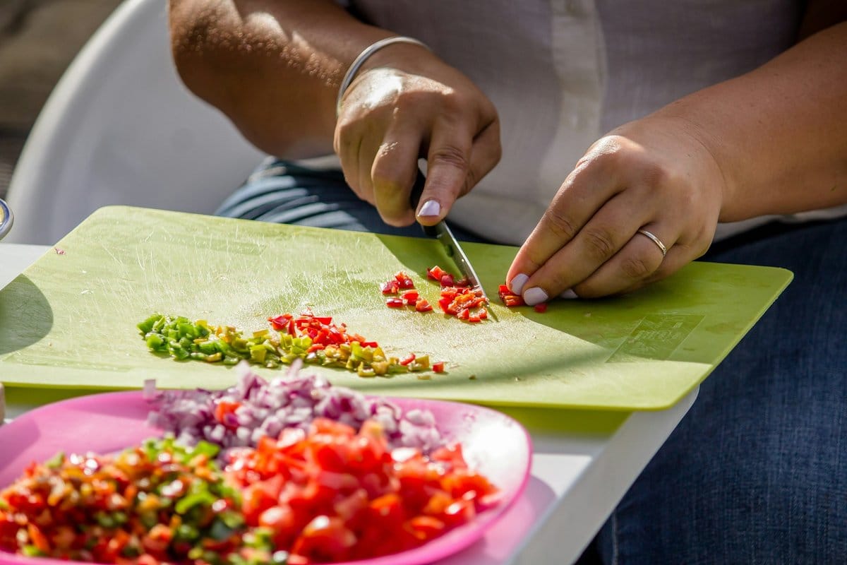 Chopping fresh tomatoes, sweet peppers, habanero, and onion for homemade Belizean cheese dip tomato sauce