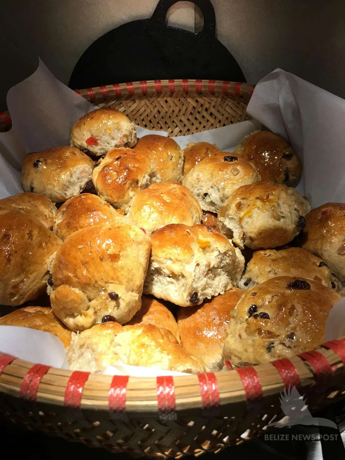 Belizean Creole buns torn open in a basket showing the raisin-studded interior, glazed and freshly baked