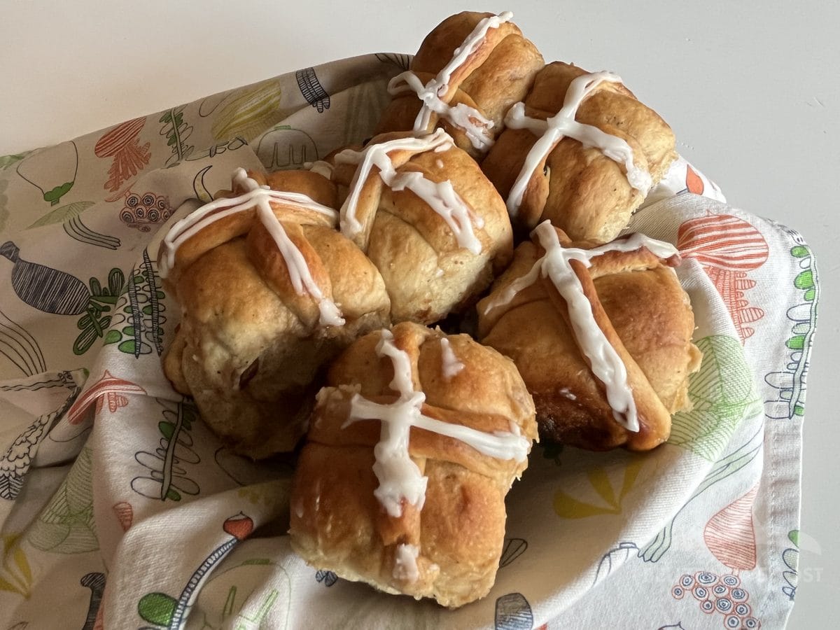 Belizean hot cross buns with white icing crosses in a cloth-lined basket, freshly baked for Easter in Belize