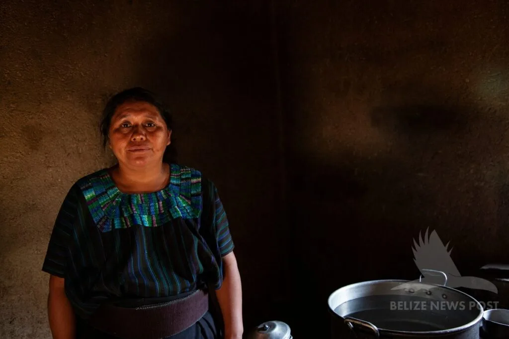 Maya woman in traditional dress standing in adobe kitchen with cooking pots — chulibuul, Belize