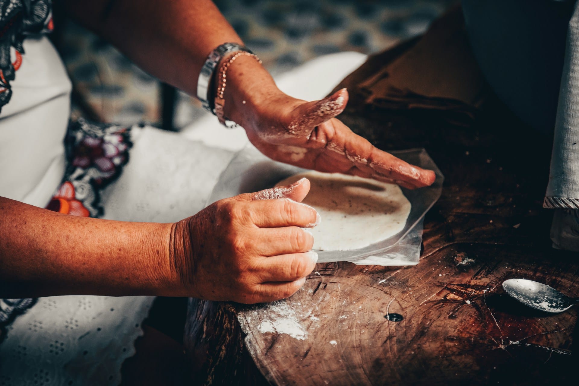 hands pressing fresh masa tortilla for panuchos yucatecos — the ridge around the edge helps the pocket form on the comal