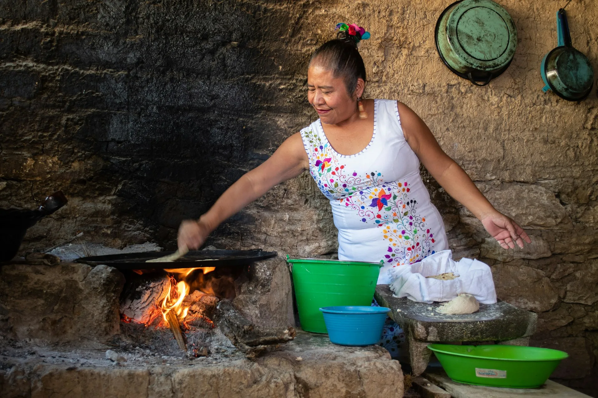 Yucatan woman cooking tortillas on a comal over a wood-fire fogon, the traditional way to make panuchos yucatecos