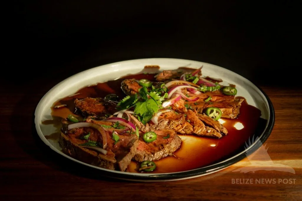Poc chuc — grilled pork with pickled red onions, jalapeños, and cilantro on a plate, Belize