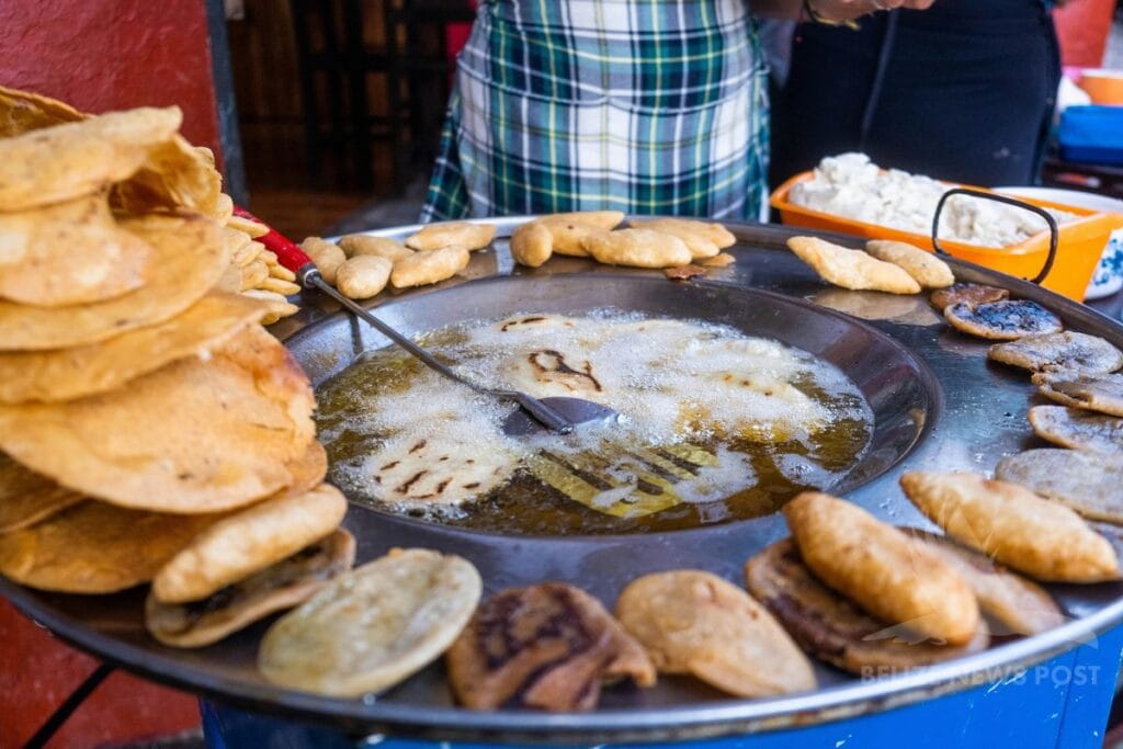 Polcanes frying in oil in a large pan, with white cheese and tostadas at a street food stall