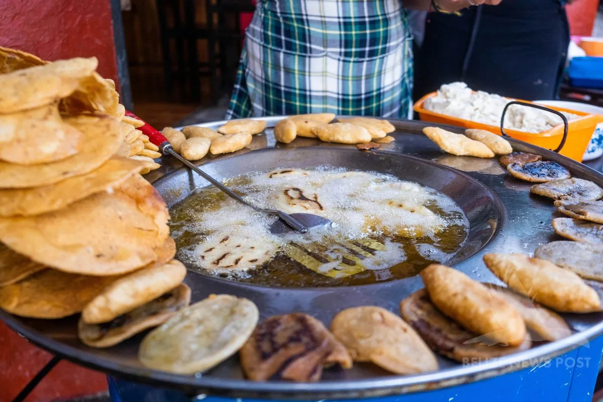 Polcanes frying in oil in a large pan, with white cheese and tostadas at a street food stall