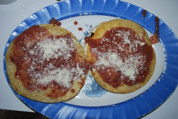 Tortillas topped with Honduran quesillo cheese and tomato sauce