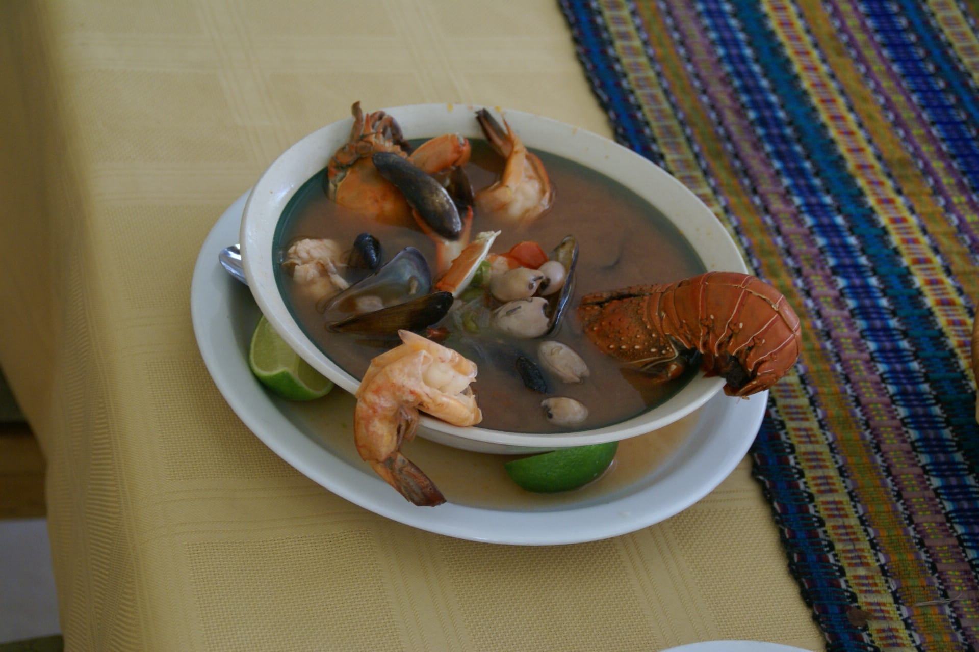 A bowl of Salvadoran mariscada showing shrimp, crab, and fish in a golden cream broth