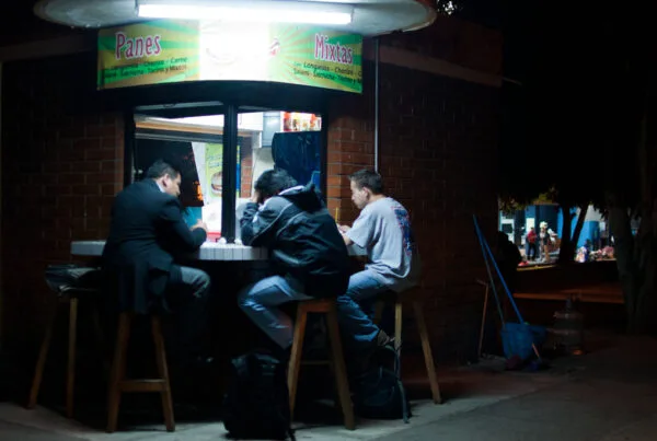 Guatemalan shuco street cart at night, menu listing longaniza chorizo carne salchicha