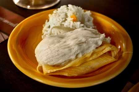 Guatemalan chuchito, a small corn-masa tamale in an open corn husk, served with rice