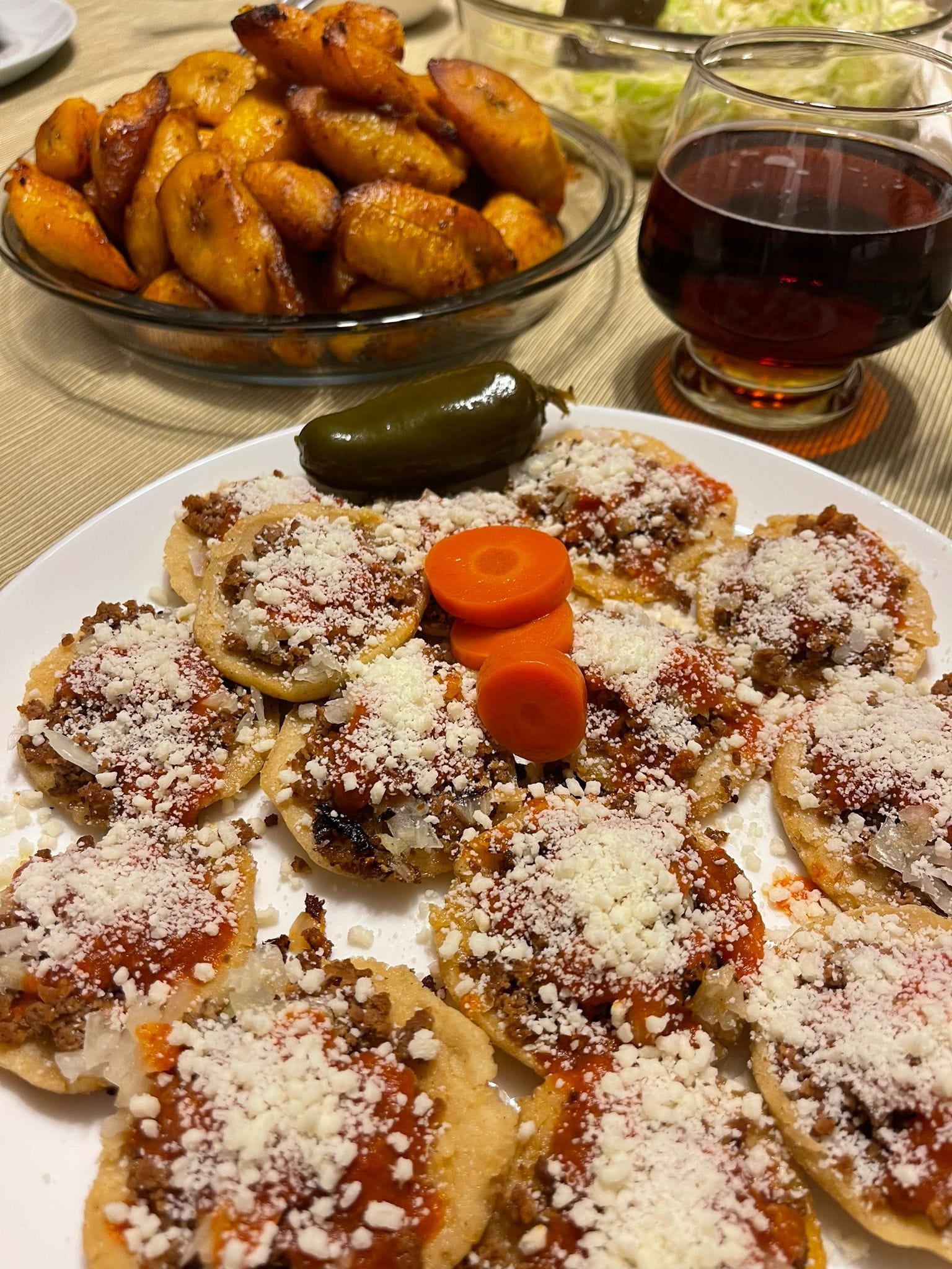 A plate of Guatemalan garnachas: small fried corn tortillas topped with meat, tomato chirmol, pickled cabbage curtido, and crumbled dry cheese