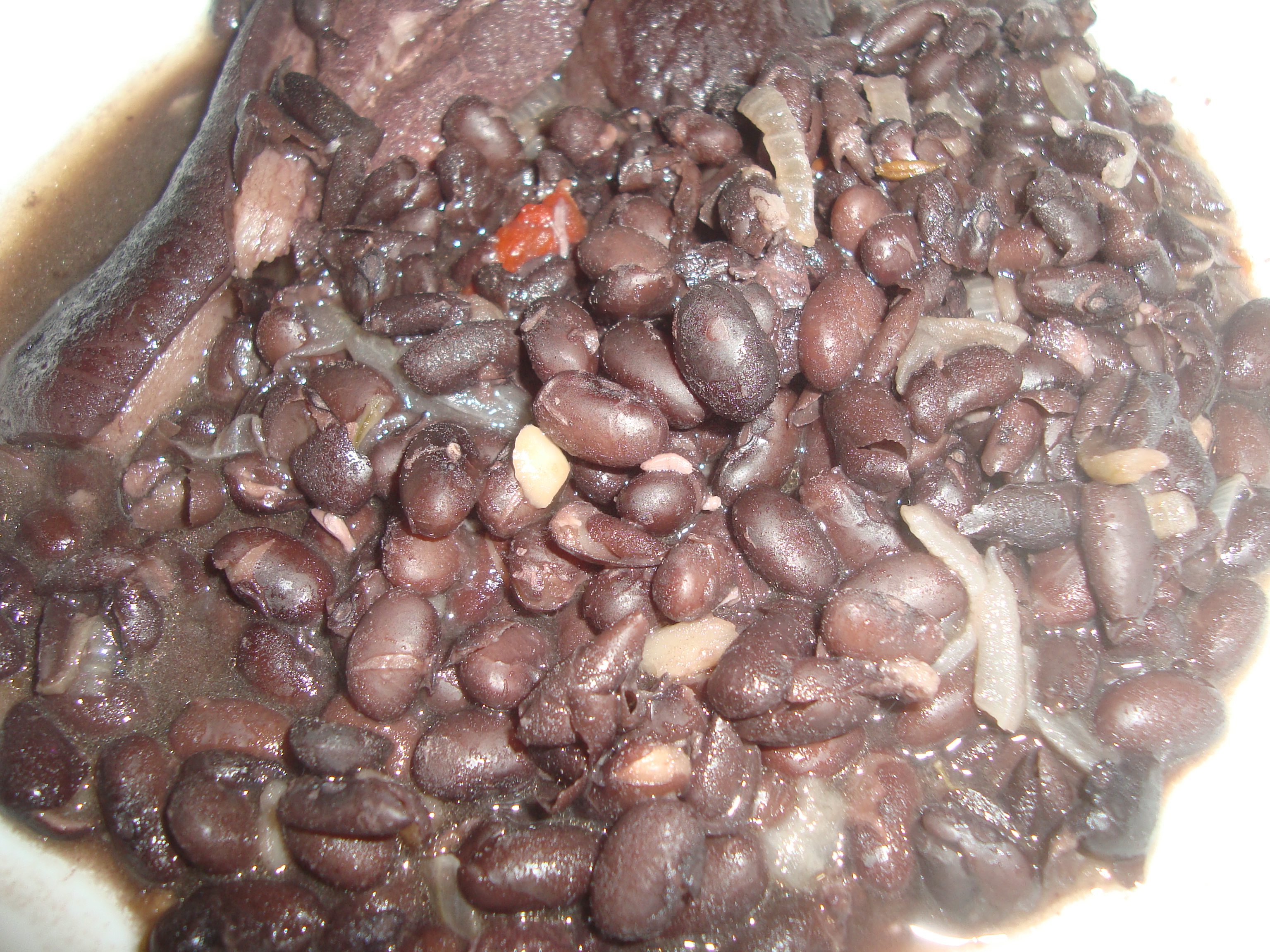 Black beans (guiso de frijoles negros) cooking in a pan — the folding stage of making frijoles volteados