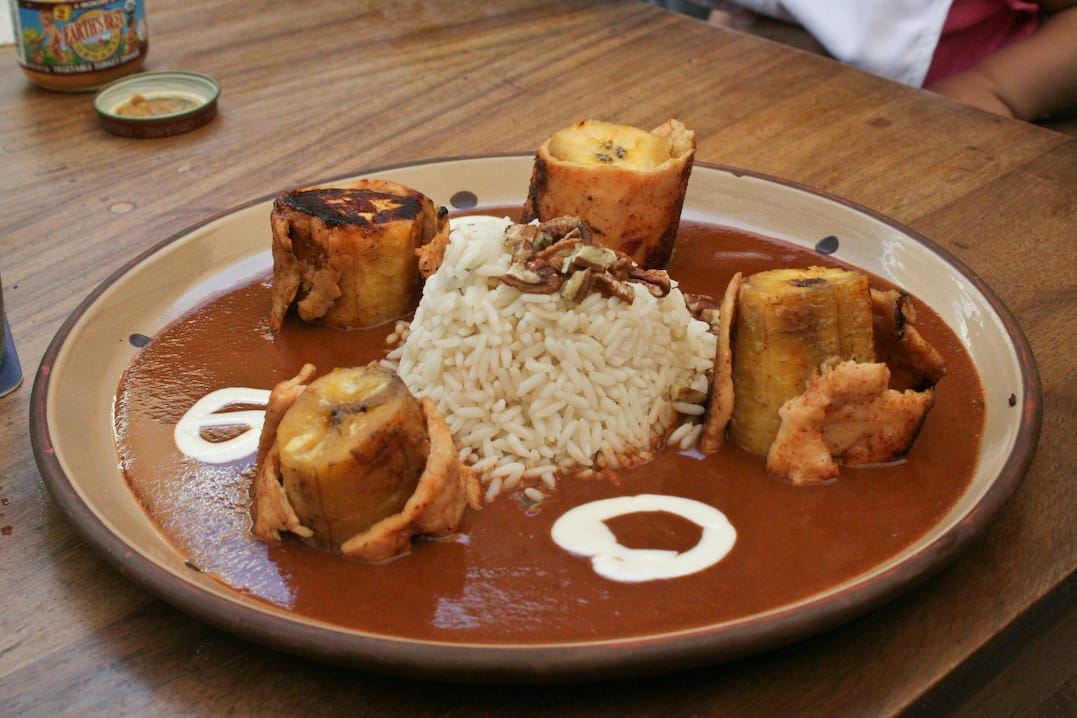Mole de platano: fried plantains bathed in sweet Guatemalan chocolate mole sauce, garnished with toasted sesame seeds
