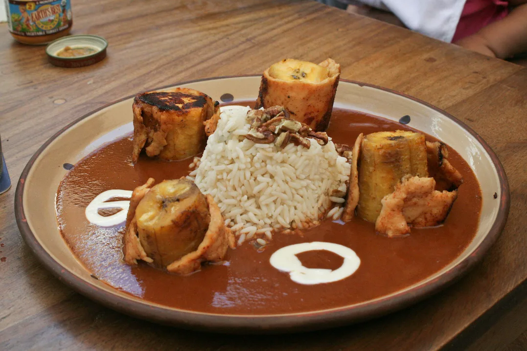 Mole de platano: fried plantains bathed in sweet Guatemalan chocolate mole sauce, garnished with toasted sesame seeds