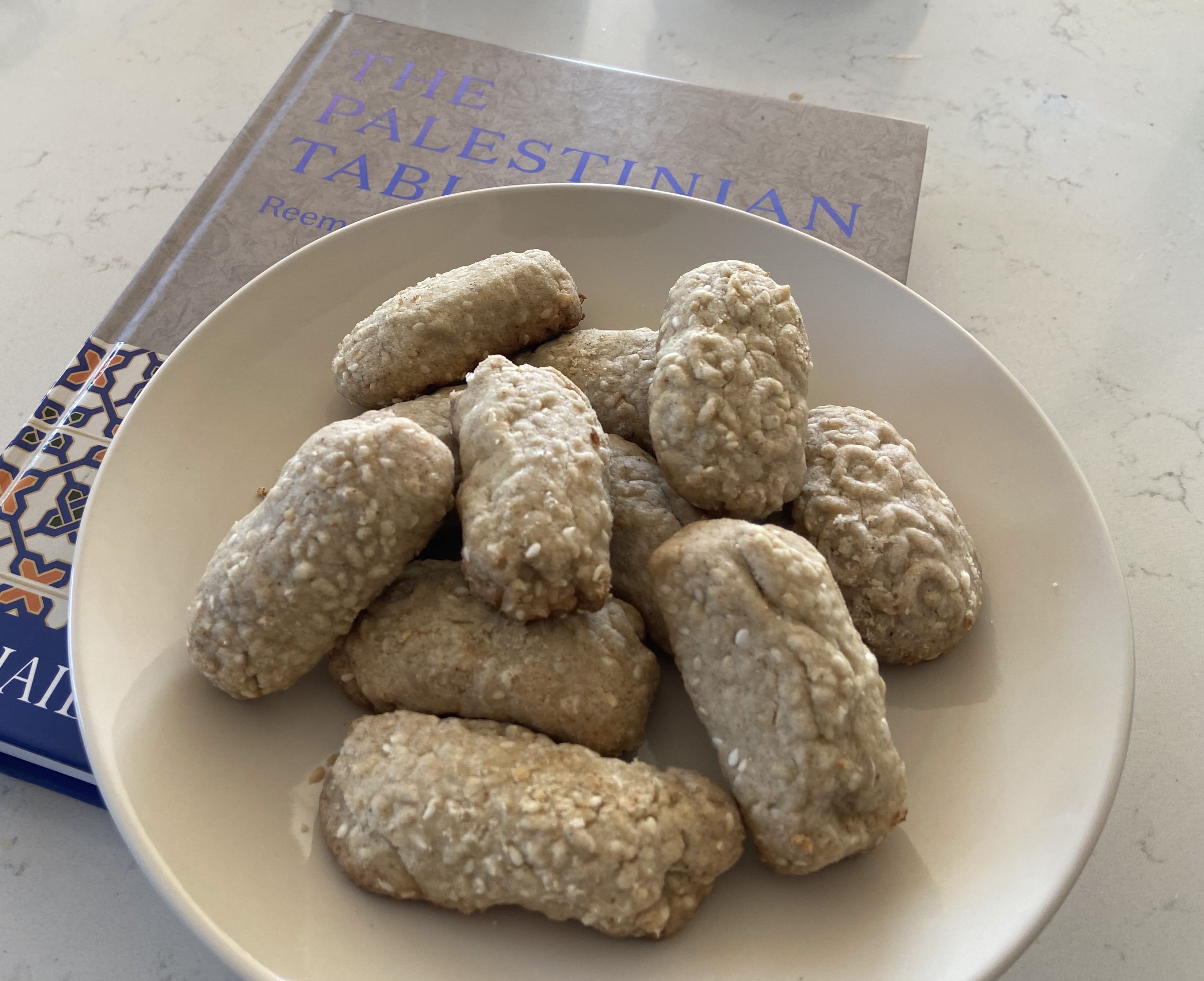Round, flat sesame seed cookies on a plate, similar to Guatemalan champurradas
