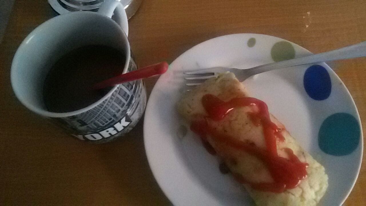 A Honduran tamale wrapped in corn husk served with a cup of coffee
