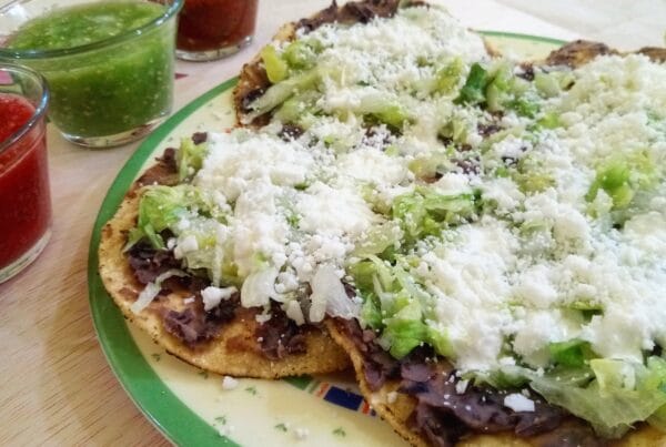 Crisp fried corn tortillas topped with refried beans and grated dry cheese, the same beans-and-cheese build as catrachas