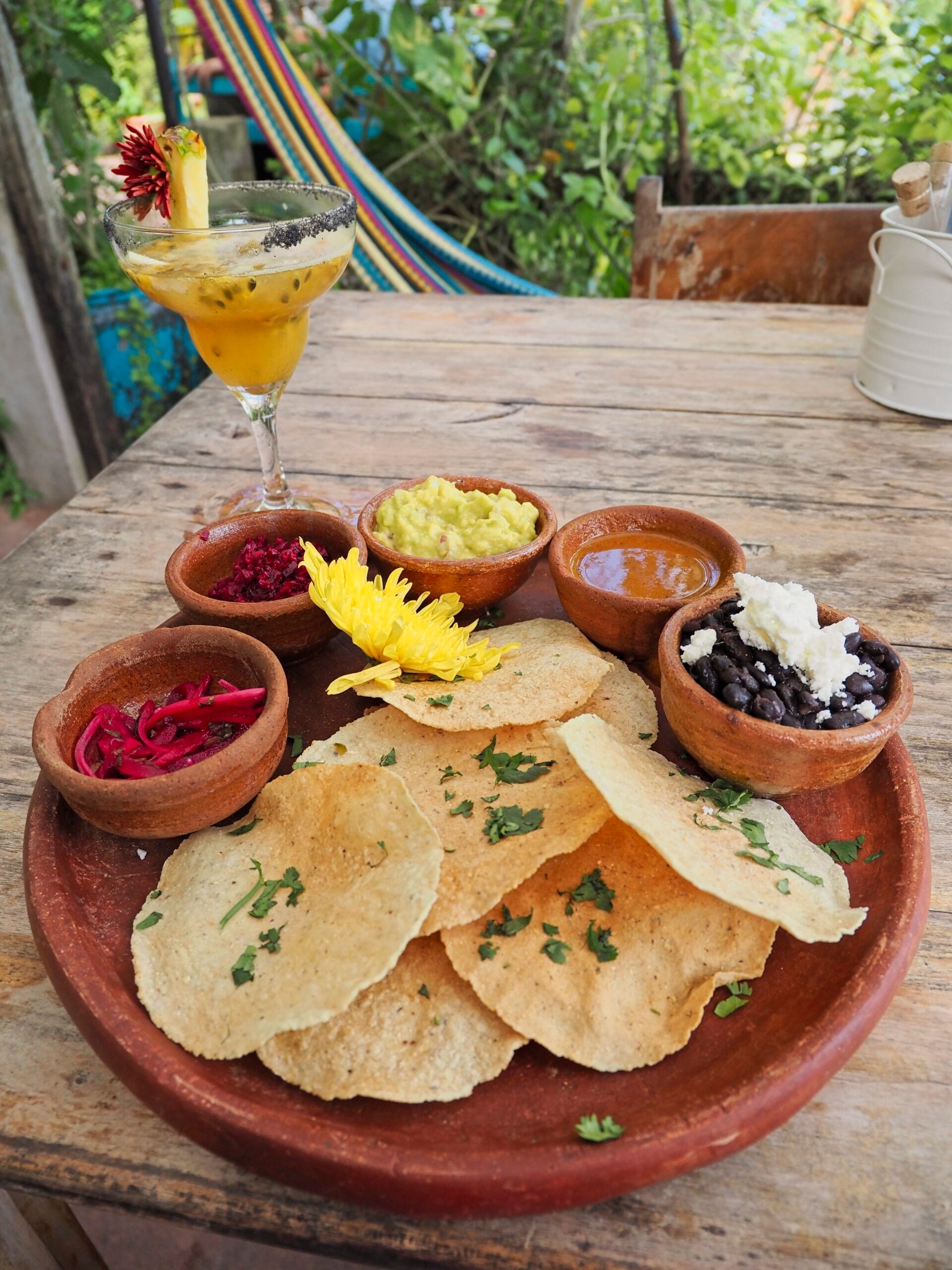 Three Guatemalan tostadas topped with refried beans, guacamol, and tomato salsa, finished with onion, parsley, and grated queso seco