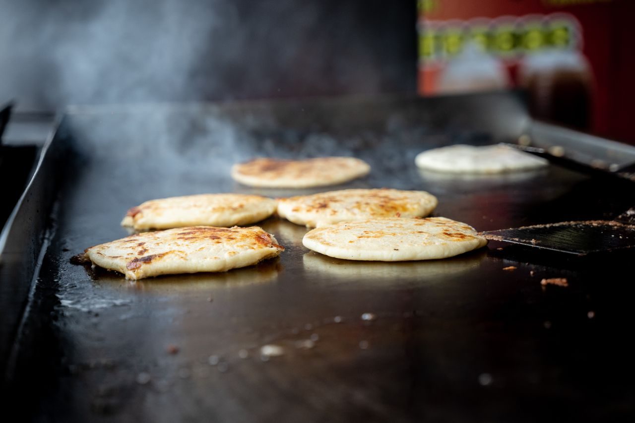 Flour tortillas browning on a hot griddle at a Honduran food stall