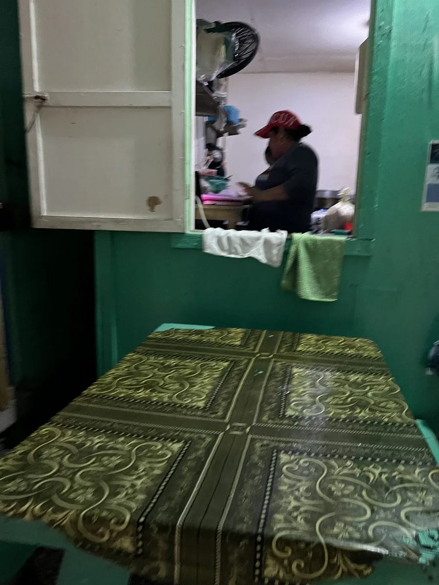 A Belizean cook preparing food at a green roadside tortilla stand