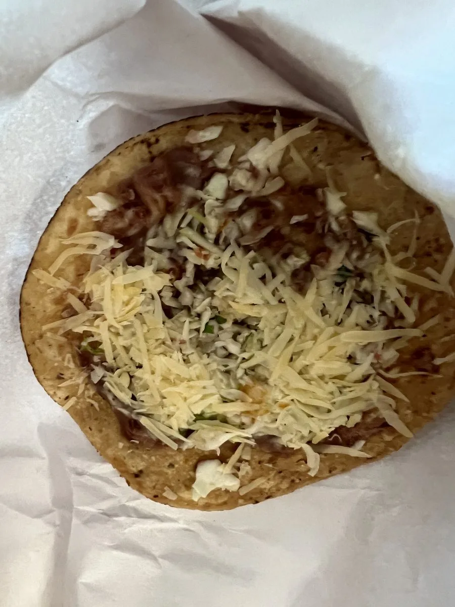 Belizean garnache, a crisp fried tortilla topped with refried beans and grated cheese