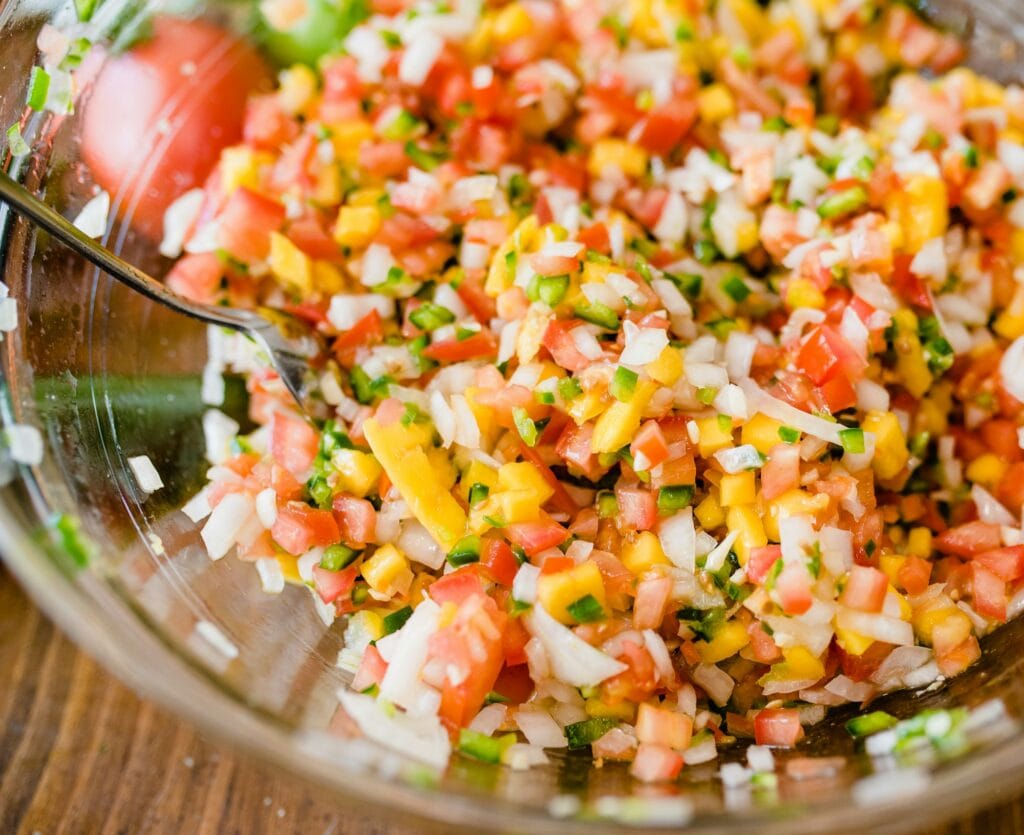 Glass bowl of Honduran chismol with finely chopped tomato, onion, green bell pepper and cilantro