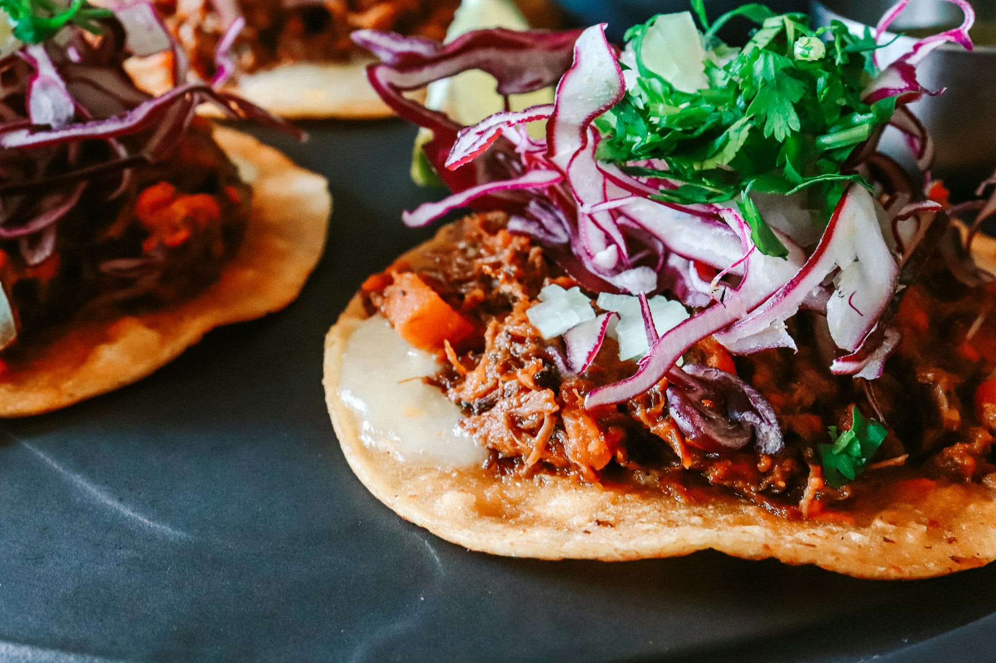 Plate of Honduran enchiladas: crispy fried corn tortillas topped with seasoned beef, shredded cabbage, and onion