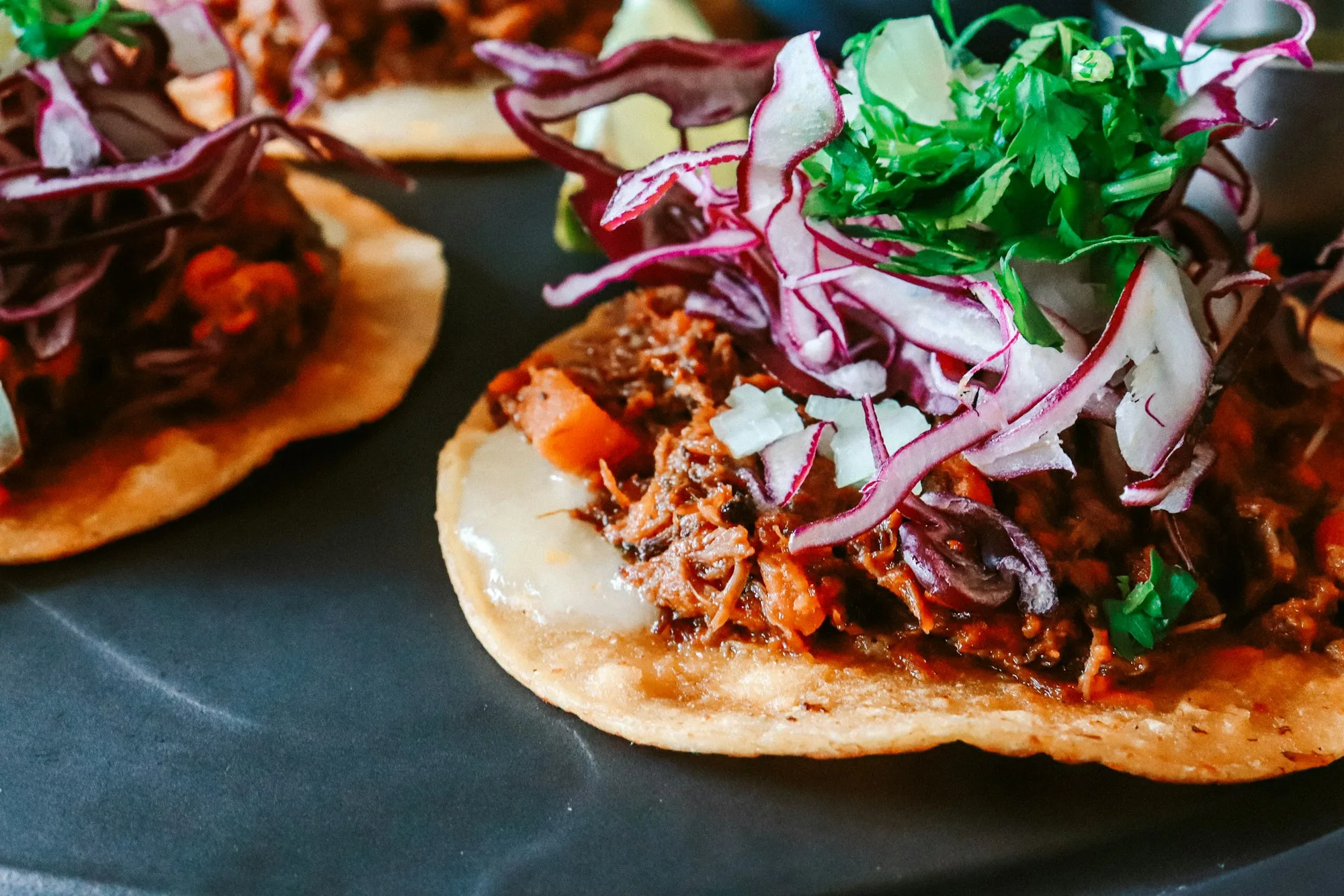 Plate of Honduran enchiladas: crispy fried corn tortillas topped with seasoned beef, shredded cabbage, and onion