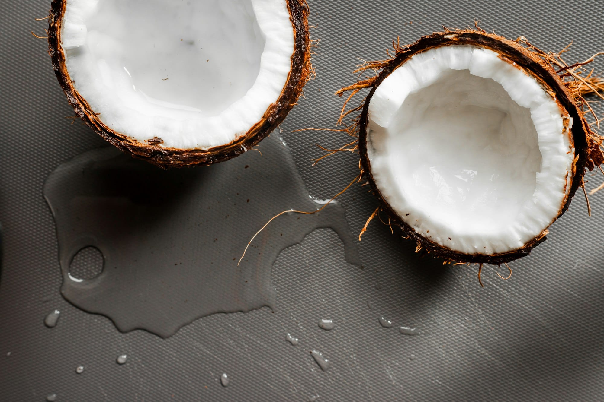 A fresh coconut split open with coconut milk, the base of pan de coco