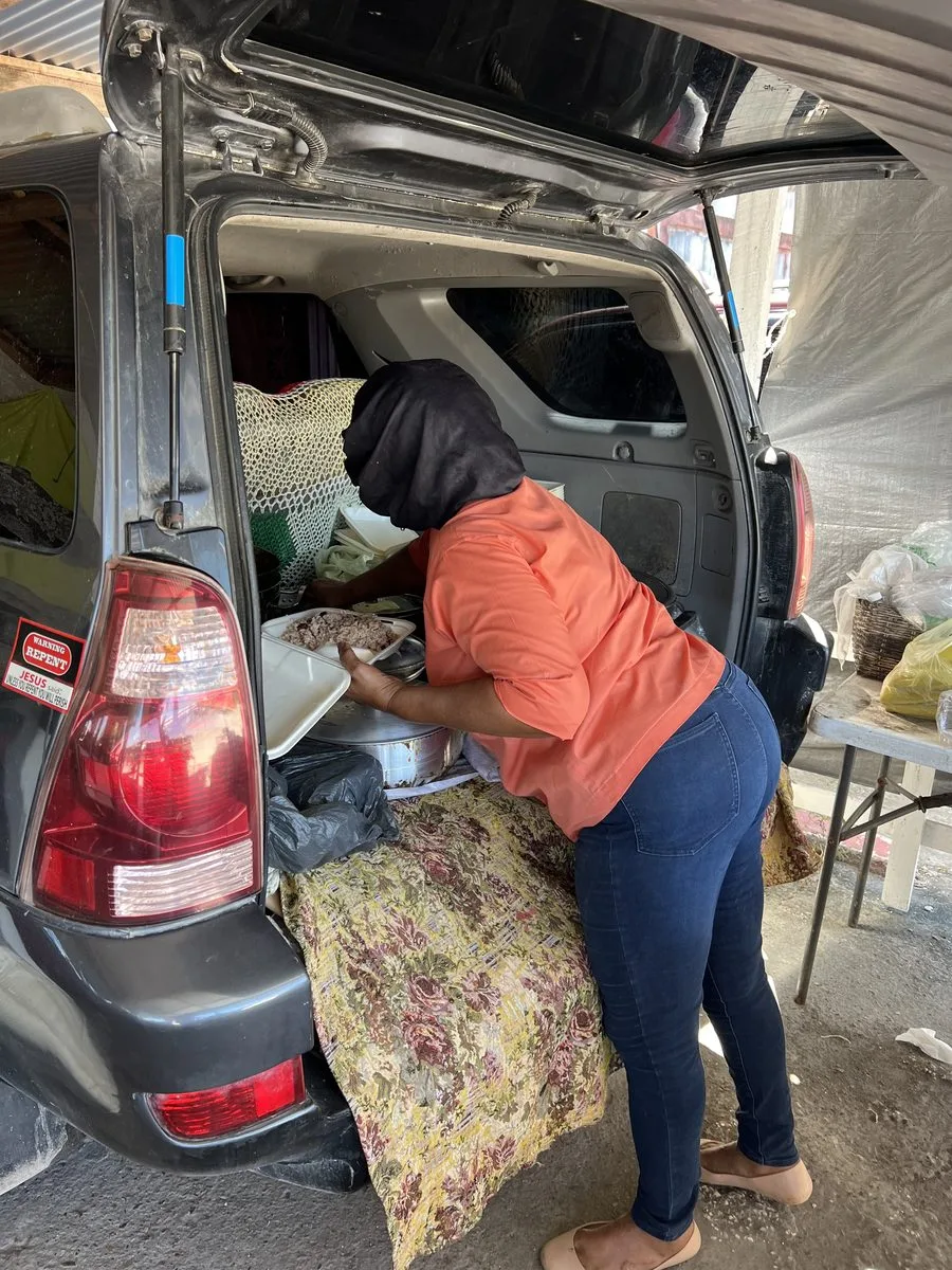 Margaret serving Belizean stew and rice from the back of her SUV near Philip Goldson airport
