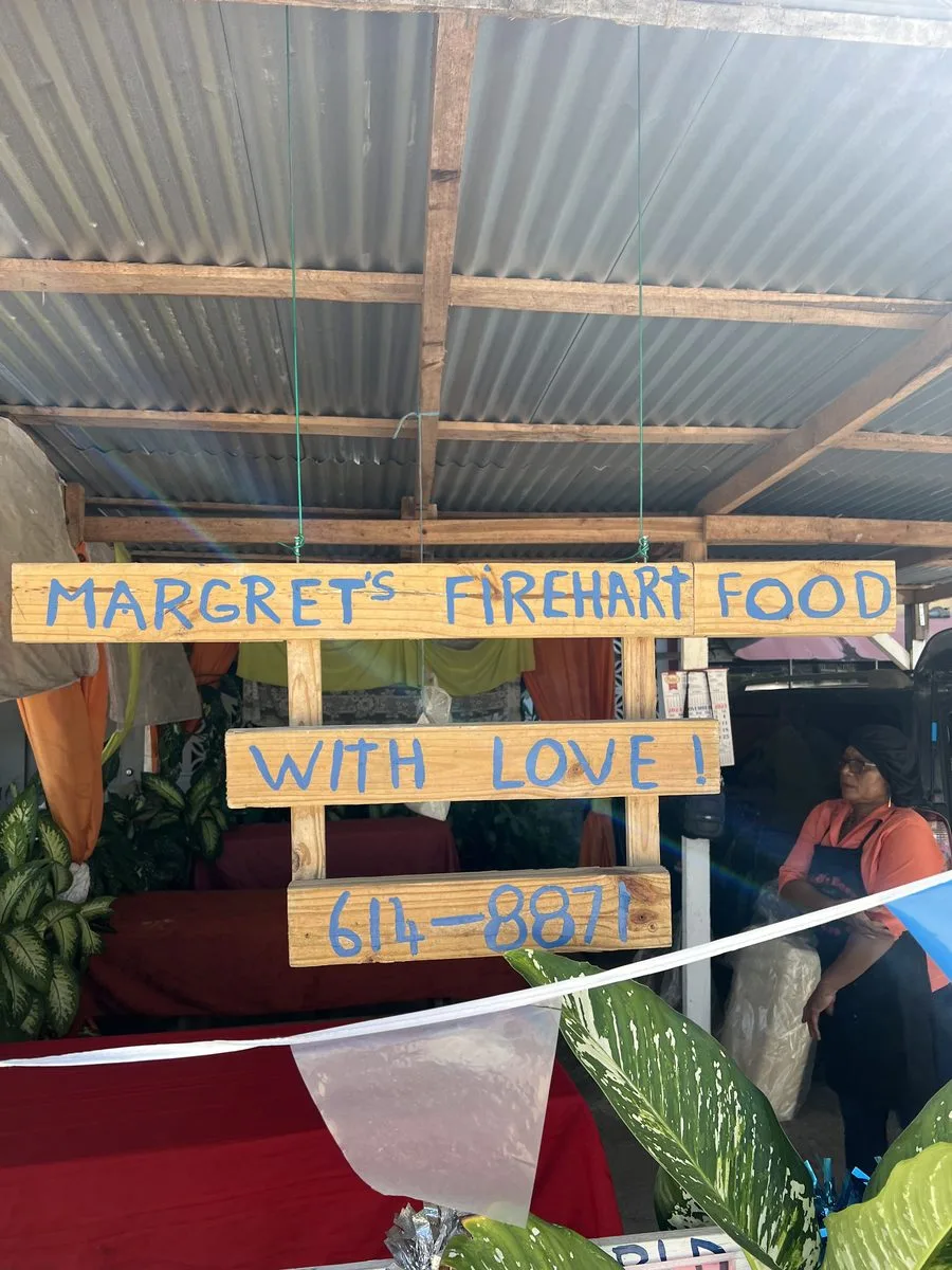 Hand-painted Margaret's Fireheart Food sign reading With Love at the Belize airport stand