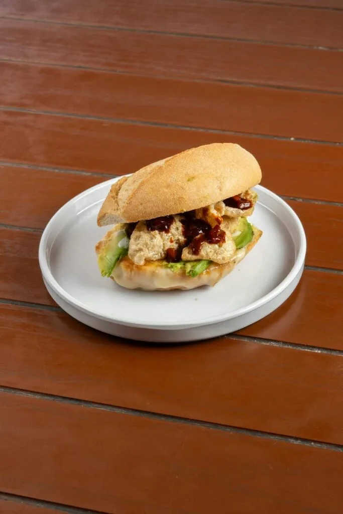 A Salvadoran chicken sandwich (pan con pollo) on a crusty roll