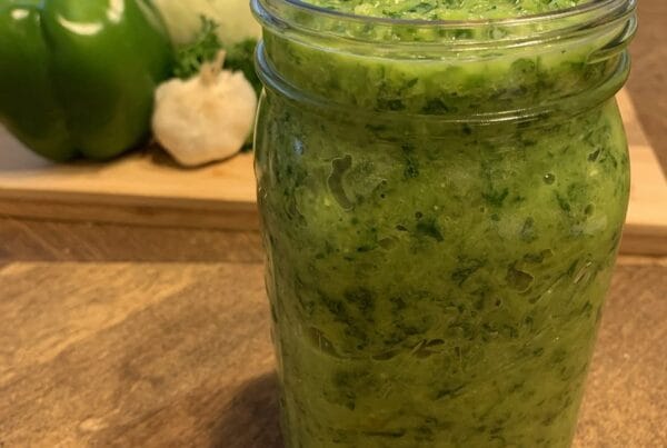 Homemade Haitian epis in a mason jar with green bell pepper, onion and garlic, the base for diri ak djon djon