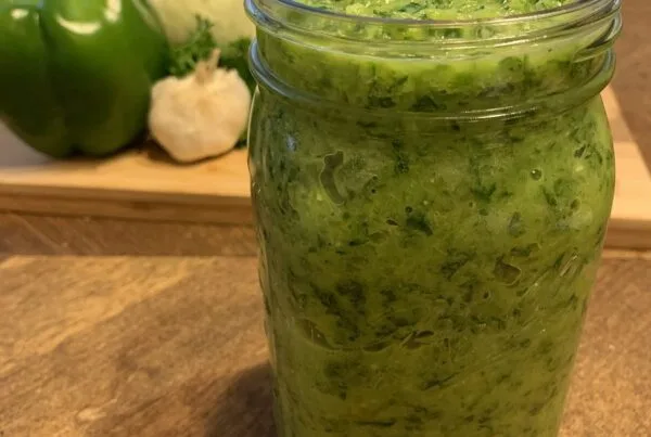 Homemade Haitian epis in a mason jar with green bell pepper, onion and garlic, the base for diri ak djon djon