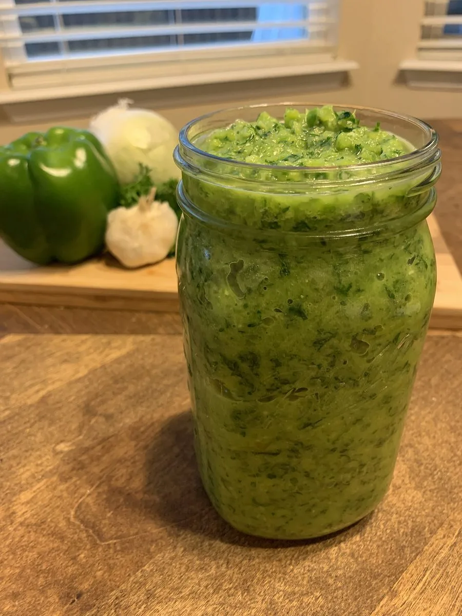 Homemade Haitian epis in a mason jar with green bell pepper, onion and garlic, the base for diri ak djon djon