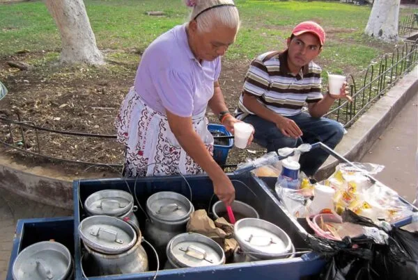 A Salvadoran street vendor serves hot atoles from aluminum pots