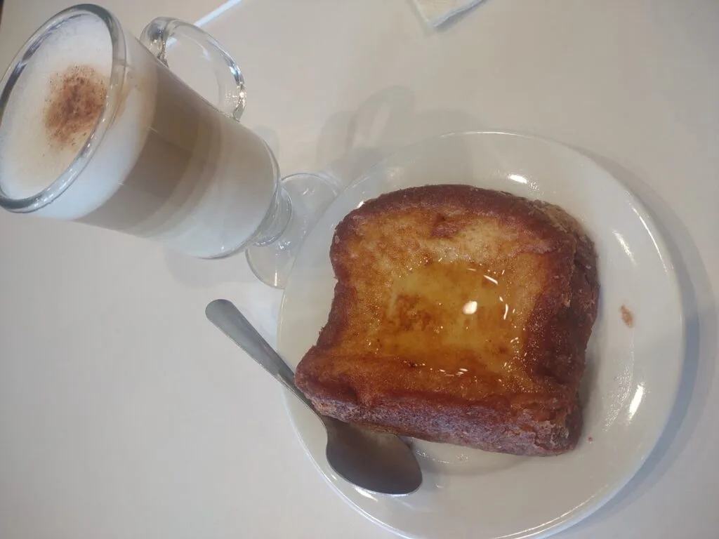 Salvadoran torrejas, a fried egg-bread slice glossy with syrup, served with a hot milky drink