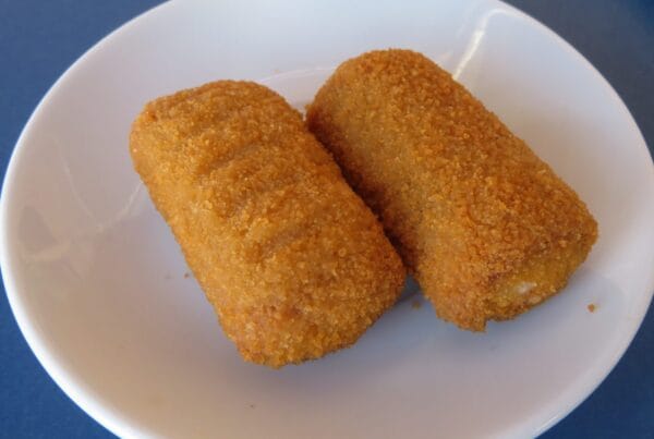 Two golden brown breaded croquettes on a white plate