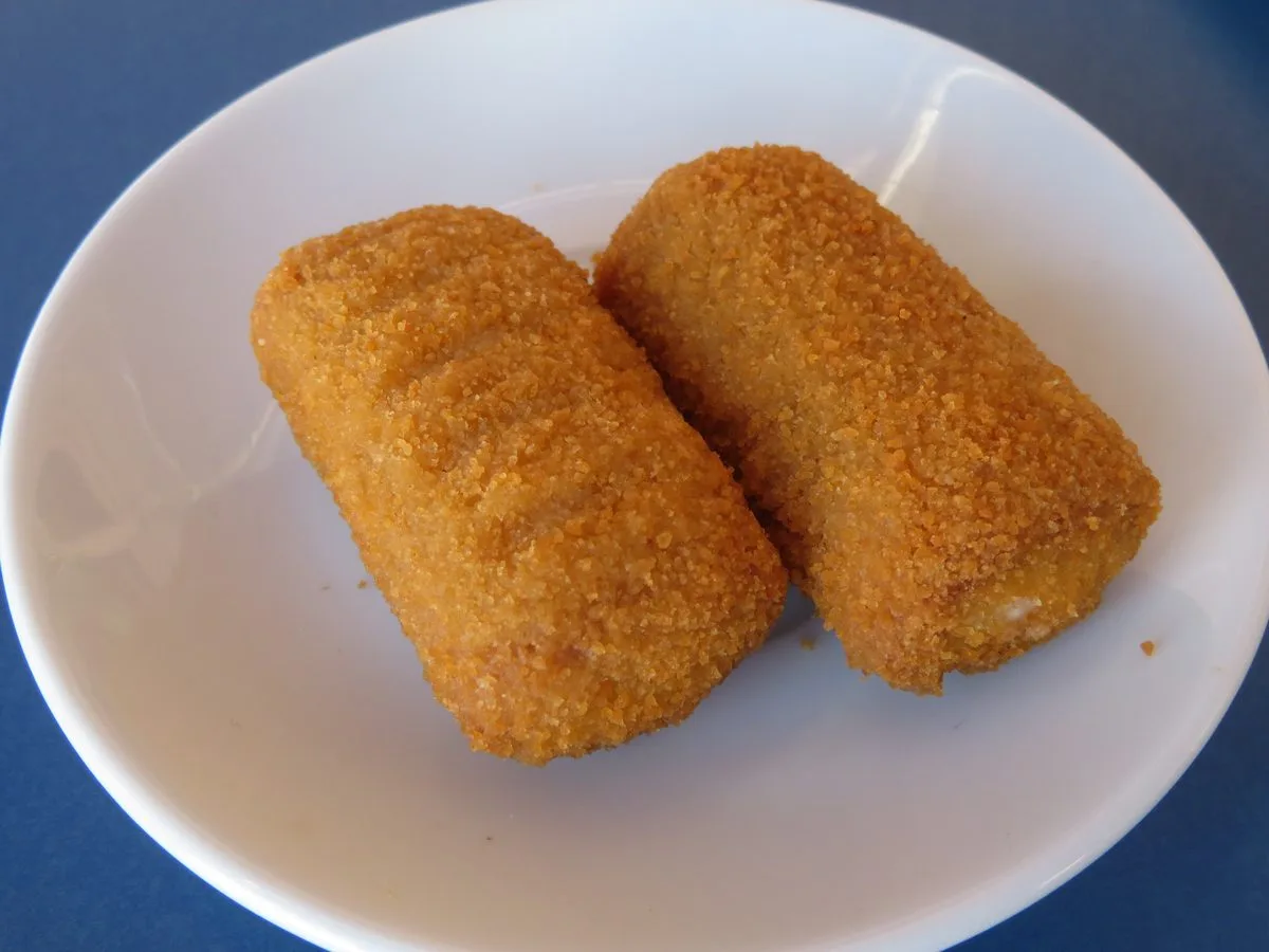Two golden brown breaded croquettes on a white plate