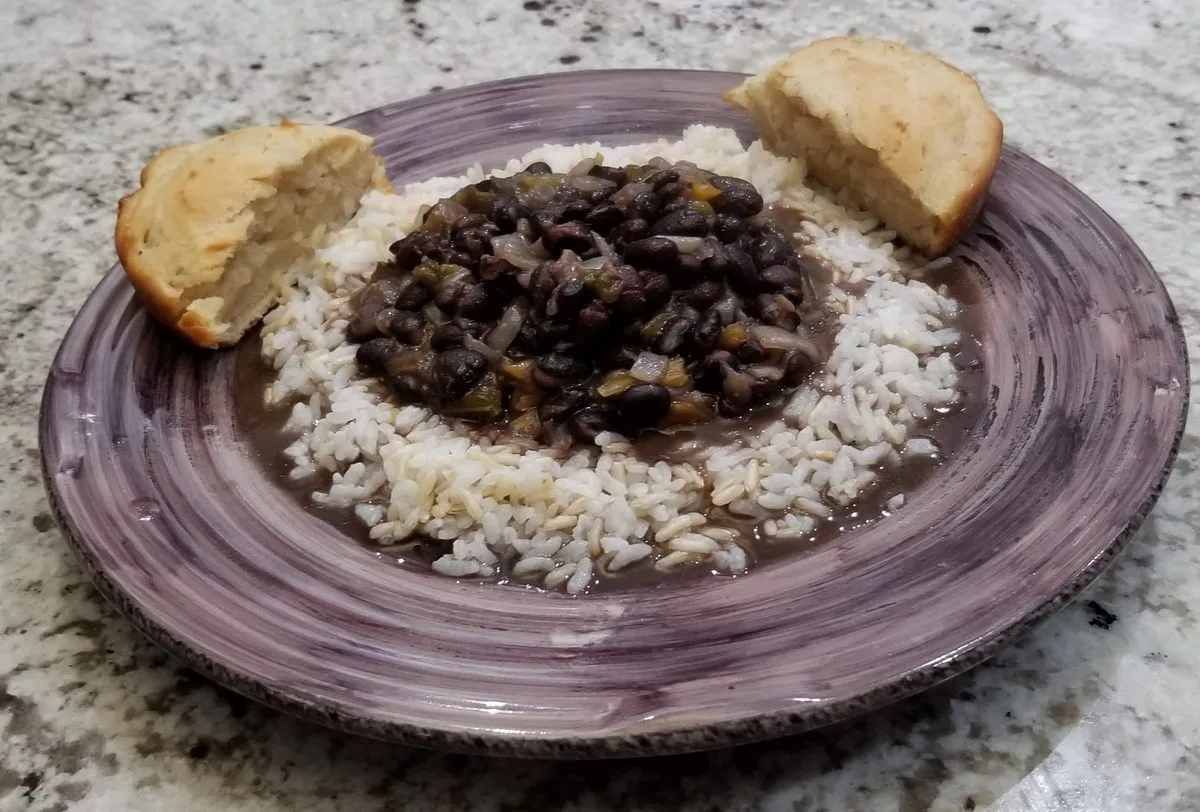 A bowl of thick black bean stew served beside white rice