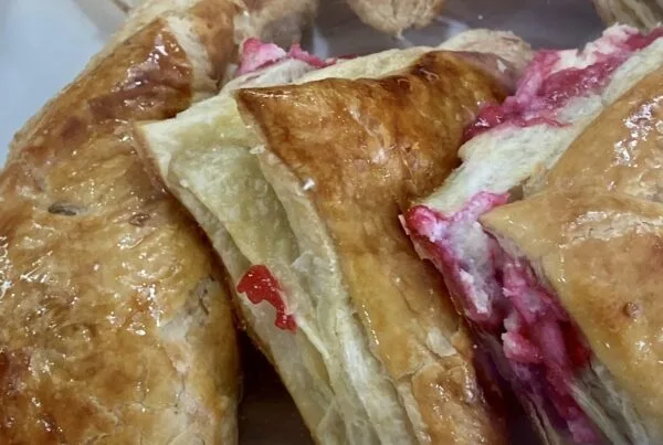Triangular guava and cheese pastelitos, glazed and stacked in a Cuban bakery case