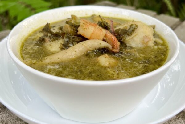 Jamaican pepperpot soup, a thick green callaloo soup with spinners, served in a white bowl
