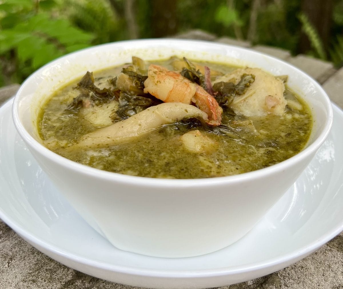 Jamaican pepperpot soup, a thick green callaloo soup with spinners, served in a white bowl
