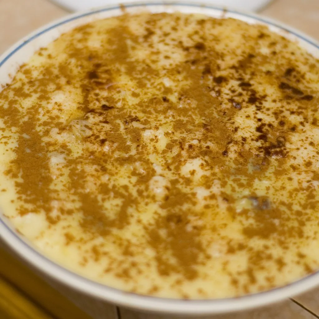 A bowl of rice pudding dusted heavily with ground cinnamon, the way arroz con dulce is finished