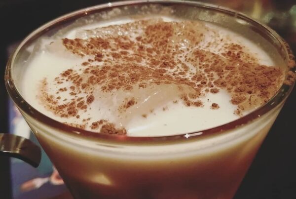 A glass of Puerto Rican coquito dusted with cinnamon