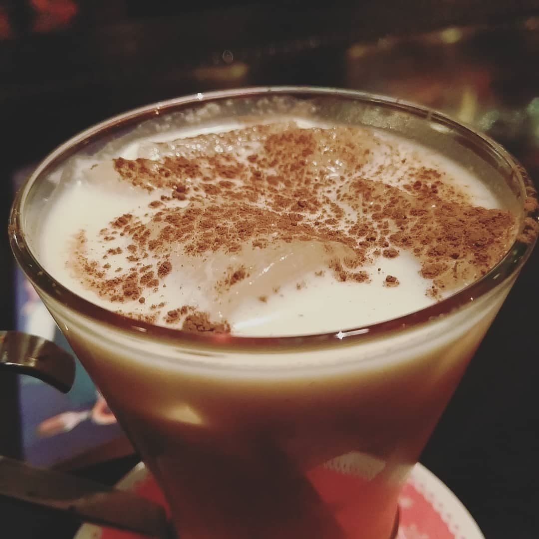 A glass of Puerto Rican coquito dusted with cinnamon