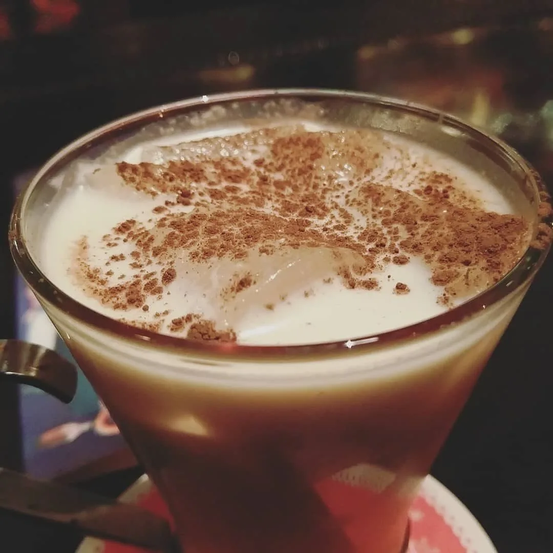 A glass of Puerto Rican coquito dusted with cinnamon